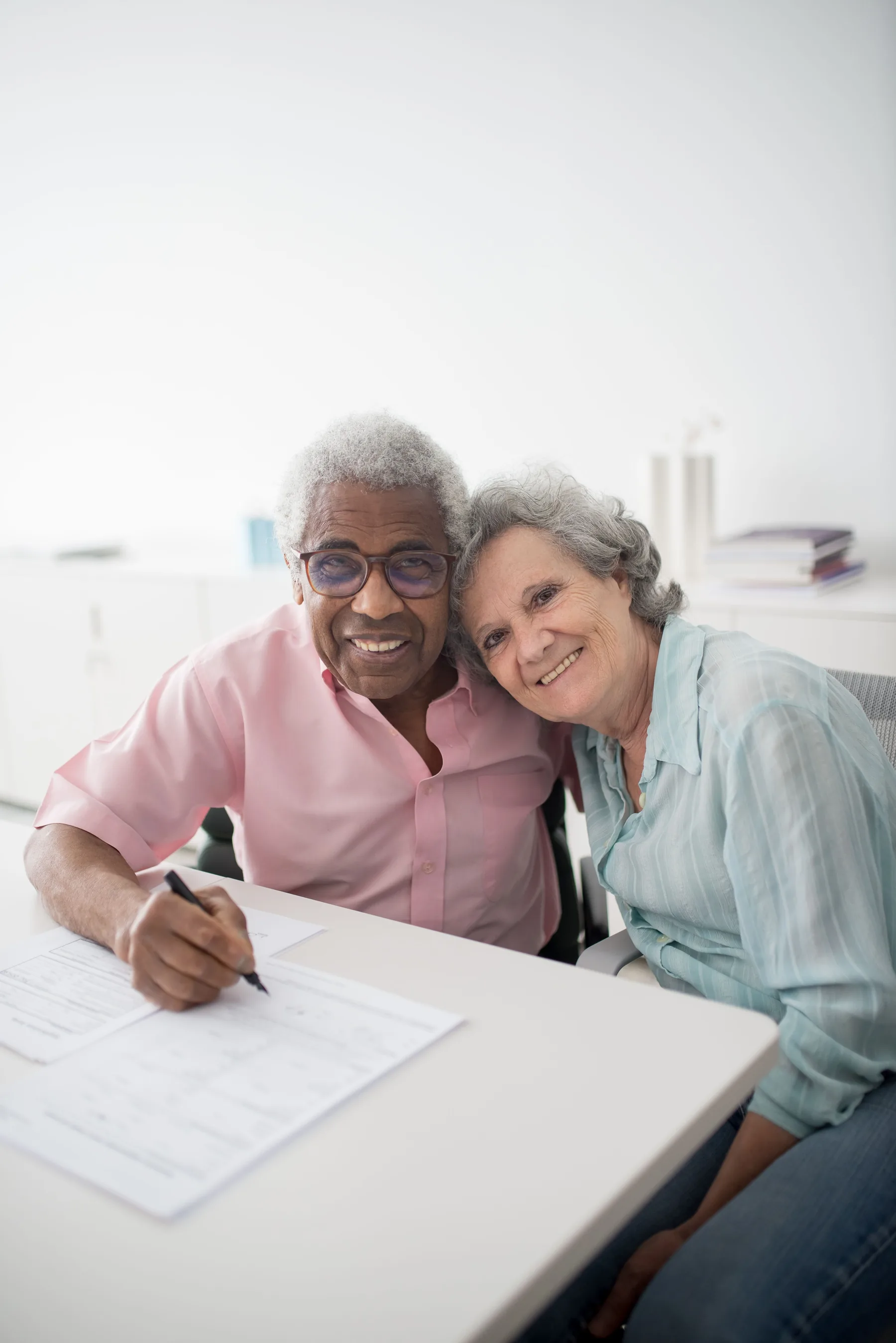 Older couple smiling while completing paperwork